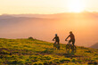 © 24K-Production - Mother and daughter cycling uphill with mountain bikes at a sunset.