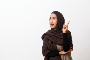Portrait of happy asian muslim woman wearing a veil or hijab pointing or presenting something above her. Isolated on white background with copy space