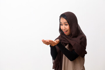 A portrait of happy asian muslim woman wearing a veil or hijab poiting or presenting something. Isolated on white background with copy space