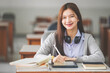 © EduLife Photos - Stock photo of a young teenage woman Asian college student in student uniform studying and writing on digital tablet in a university classroom