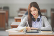 © EduLife Photos - Stock photo of a young teenage woman Asian college student in student uniform studying and writing on digital tablet in a university classroom