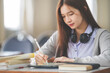 © EduLife Photos - Stock photo of a young teenage woman Asian college student in student uniform studying and writing on digital tablet in a university classroom