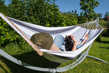 Woman In Hammock With A Black Cat Enjoying Good Weather In A Rural Environment.