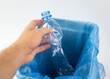 Segregacja plastikowych śmieci. Butelka plastikowa wrzucana do odpowiedniego kosza na śmieci.