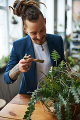 Cheerful young man cleaning plant leaves with brush