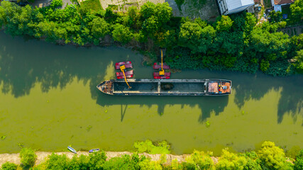 Aerial view of river, canal is being dredged by excavator