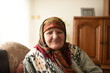 © Minet - a very old woman in traditional Muslim clothes sitting in the house next to the window
