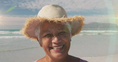 Canvas Print - Animation of glowing light over senior woman smiling by seaside