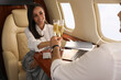 © New Africa - Colleagues clinking glasses of champagne at table in airplane during flight