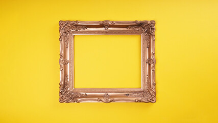 empty ornate gold picture frame on yellow wall background