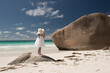 © Milou Dirks - Young girl in white dress and wide hat on tropical beach of Indian Ocean at Seychelles on rock