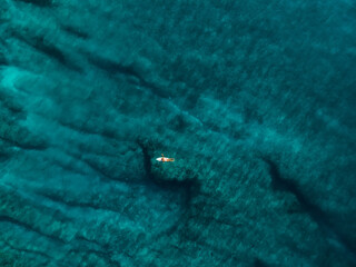 Wall Mural - Surfer woman with surfboard in blue ocean. Aerial view with surface of sea