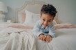 © VK Studio - Happy curly afro american boy laying on bed and smiling at camera