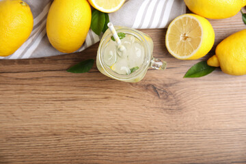 Cool freshly made lemonade and fruits on wooden table, flat lay. Space for text