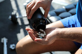 Fototapeta  - Sportsman with bottle of pills in gym, closeup. Doping concept
