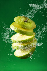 Poster - Sliced green apple cut splashing water on green background