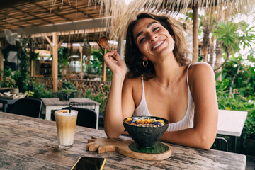 Wall Mural - Smiling woman having tasty breakfast in tropical garden