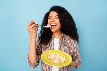 Wall Mural - Photo of hungry charming dark skin woman dressed checkered shirt eating cornflakes closed eyes isolated blue color background