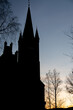 Silhouette of a church in sunset light framed by dark fine detail tree branches