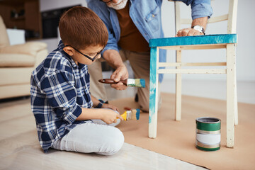 Wall Mural - Little boy with grandfather painting wooden chair in blue at home.