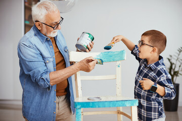 Wall Mural - Grandfather and grandson painting chair in blue color while repairing furniture at home.