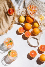 Summer Fashion Flat Lay On White Background. Holiday Party, Vacation, Travel, Tropical Concept. Straw Hat, Refreshing Drinks And Citrus Fruits. Palm Shadow And Sunlight, Sun. Top View.