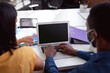 © wavebreak3 - Diverse male and female colleague in face masks sitting at desk discussing and using laptop