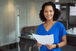© wavebreak3 - Portrait of smiling african american businesswoman holding paperwork standing in office