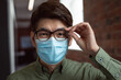 © wavebreak3 - Portrait of asian businessman wearing face mask in office holding glasses and looking to camera