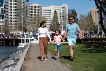 Wall Mural - Happy family with little child son walking outdoors against city landscape.