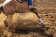 A horse is barrel racing in an up close photo with dirt flying.