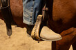 A close up view of a cowboy boot in a stirrup at a rodeo.