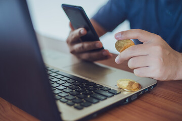 Man holding bitcoin while using smartphone with selective focus on bitcoin, Cryptocurrency modern financial and trader concept.