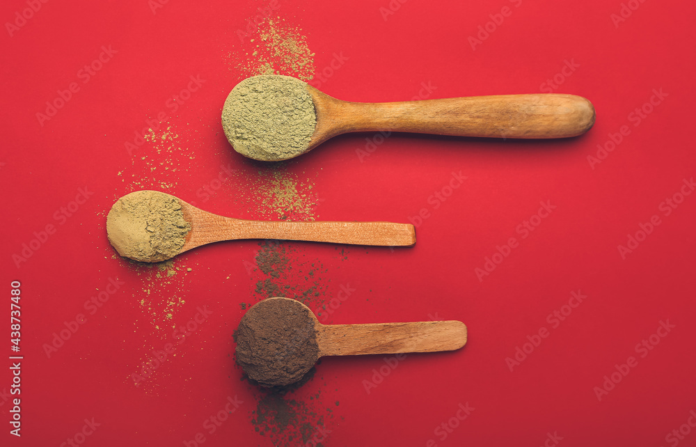 Dry henna powder in spoons on color background
