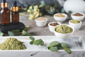 Composition with dry henna powder in bowls and bottles of essential oil on grunge background, closeup