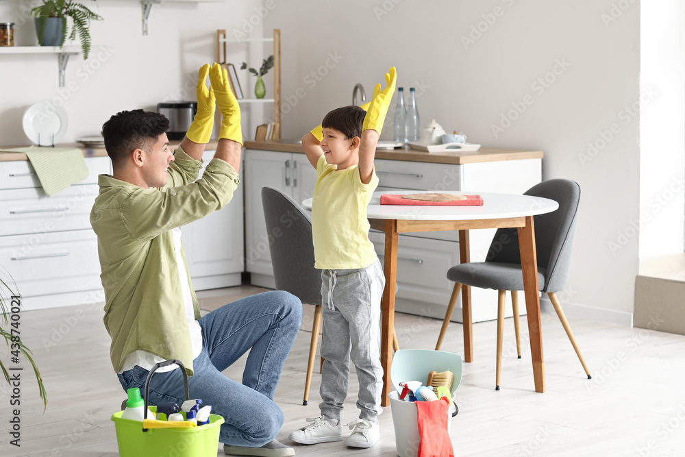 Father and son with cleaning supplies in kitchen