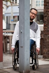 Poster - Man in wheelchair hiding behind metal post