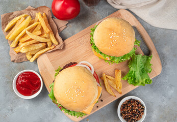 Lunch with burgers. Two large hamburgers, French fries and gravy on a gray background.