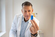 © epiximages - male chemist, scientist works at standing table and examines blue liquids in small vials and wears white coat