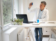 © epiximages - male chemist, scientist works at standing table and examines blue liquids in small vials and wears white coat