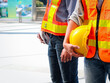© Stella - Yellow helmet in hand of male engineer who wearing safety vest and helmet, staff worker confidential standing at outside office in downtown city.