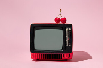 Wall Mural - Creative layout with old tv and bright red cherry on pastel pink background. Retro style aesthetic idea. Vintage television and summer fruit concept.