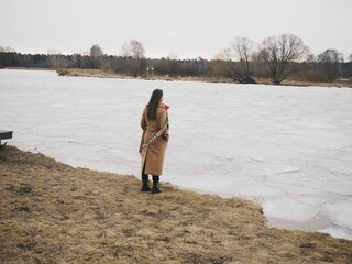 a young woman walks along the river in autumn, and then warms herself with hot tea in a cafe