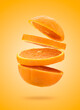 Orange fruit sliced in flying sections on colored background