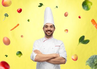 Wall Mural - cooking, culinary and people concept - happy smiling male chef in toque and jacket with crossed arms over vegetables on illuminating yellow background