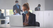 © nimito - Businesswoman sitting in office in front of computer wearing face mask