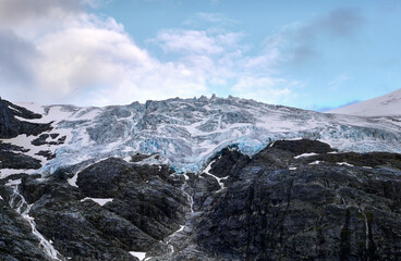 Wall Mural - Glacier on a mountain peak. Streams of glacial water flow into the mountain lake. Beautiful structure of glacier and rocks on a mountain peak. Joffre Lakes Provincial Park. British Columbia, Canada.