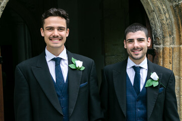 Smiling gay grooms dressed in suits leaving church after getting married