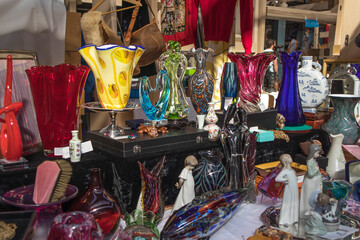 Spitalfields Antique Market. Porcelain figurines, vases, earthenware cup, plates, photo frames, bone beads, dog figures for sale at the flea market.