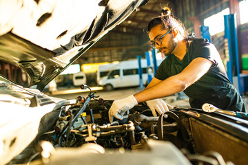 Auto mechanic standing in his workshop in sunset light background